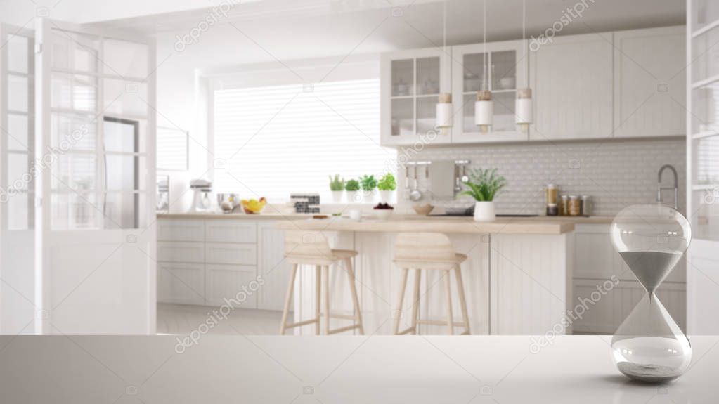White table or shelf with crystal hourglass measuring the passing time over modern white and wooden scandinavian kitchen, architecture interior design, copy space background