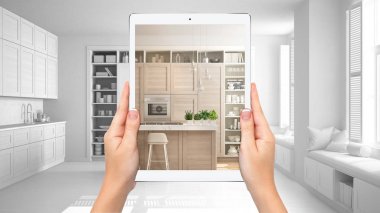 Modern beyaz ve ahşap mutfak gösteren eller tutma tablet, toplam boş proje arka plan, artırılmış gerçeklik konsepti, uygulama mobilya ve iç tasarım ürünleri simüle etmek