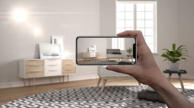 El tutan akıllı telefon, Ar uygulaması, gerçek evde mobilya ve iç tasarım ürünleri simüle, mimar tasarımcı kavramı, bulanıklık arka plan, halı ile minimalist oturma odası