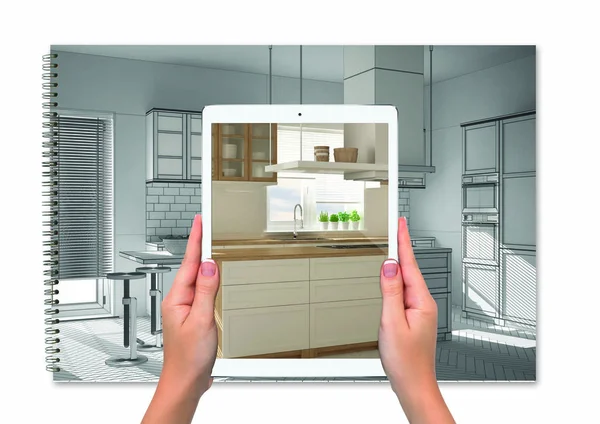 Руки держат планшет, показывающий кухню, ноутбук с эскизом чертежа на заднем плане, концепцию дополненной реальности, приложение для имитации мебели и изделий интерьера — стоковое фото