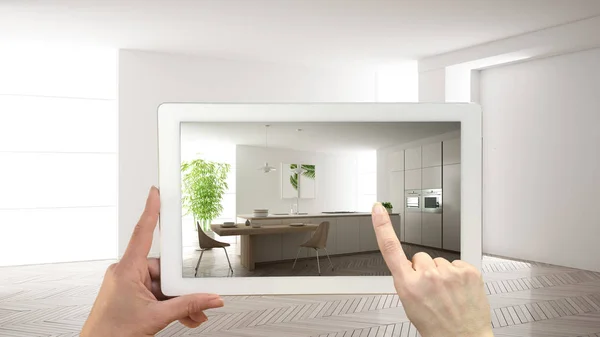 Augmented reality concept. Hand holding tablet met Ar toepassing gebruikt om te simuleren van meubelen en design producten in leeg interieur met parketvloer, moderne witte keuken — Stockfoto