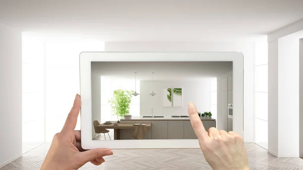 Концепция дополненной реальности. Ручной планшет с приложением AR для имитации мебели и дизайнерских изделий в пустом интерьере с паркетным полом, современной белой кухней — стоковое фото