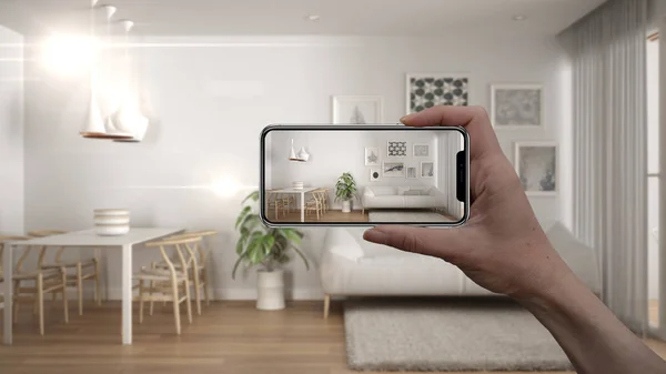 Hand holding smart phone, AR application, simulate furniture and interior design products in real home, architect designer concept, blur background, minimalist living room with carpet