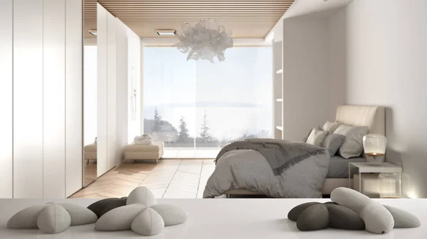 White table, desk or shelf with five soft white pillows in the shape of stars or flowers, over blurred bedroom with shower and window, minimalist architecture interior design concept