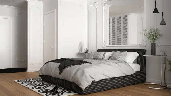 Современная белая спальня в классической комнате с настенными лепнинами, паркетным полом, двуспальной кроватью с одеялом и подушками, минималистскими тумбочками, зеркалом и декором. Концепция интерьера — стоковое фото