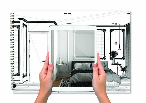 Hands holding tablet showing bedroom, notebook with blueprint sketch in the background, augmented reality concept, application to simulate furniture and interior design products