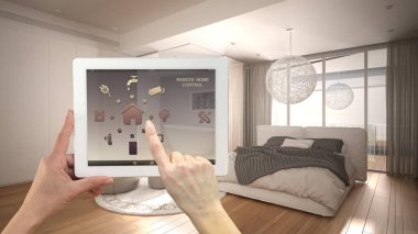 Dijital tablette akıllı uzaktan kumanda sistemi. Uygulama simgeleri olan aygıt. Minimalist, parlak yatak odası. Arka planda banyo, mimari iç tasarım.