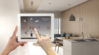 Dijital tablette akıllı uzaktan kumanda sistemi. Uygulama simgeleri olan aygıt. Minimalist modern parlak oturma odası, arka planda koltuklar ve kanepe, mimari iç tasarım.