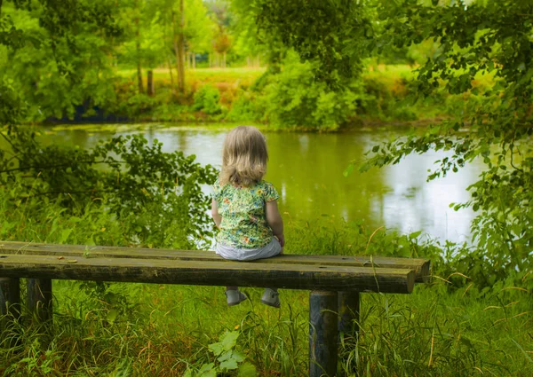 Ein Zweijähriges Mädchen Das Allein Auf Der Bank Sitzt Und — Stockfoto