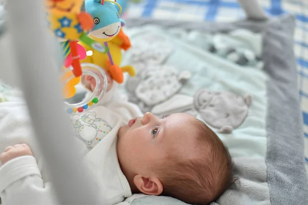 男婴玩挂在发展中的垫子上的玩具 — 图库照片