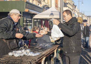 Dieppe, Fransa - 17 Kasım 2018: Alıcı ringa balığı ızgara ve patates folyo satın alır. Piyasada adil ringa balığı ve tarak shell