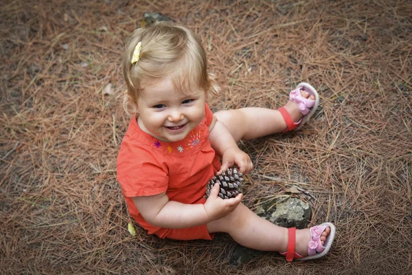 Kleines Mädchen mit einem Kegel im Wald — Stockfoto