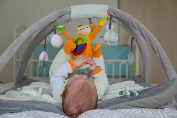 Bayi laki-laki bermain dengan mainan menggantung di mengembangkan tikar — Stok Foto