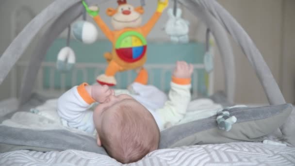 Chłopiec bawiący się z wiszącymi zabawkami na rozwijającym się mat — Wideo stockowe