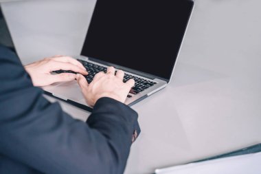 Pozitif genç iş adamı oturuyor ve belgeler ve dizüstü bilgisayarla çalışıyor,