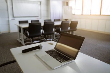 Laptop ya da defter ve toplantı odası ya da seminer salonu ile kopya alanı içinde tablo üzerinde mikrofon.