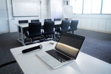 Laptop ya da defter ve toplantı odası ya da seminer salonu ile kopya alanı içinde tablo üzerinde mikrofon.