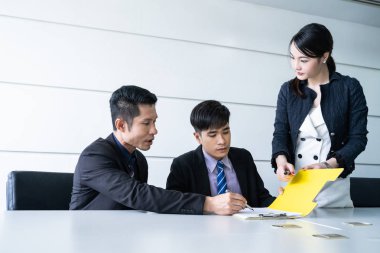 Tablo ve evrak ortağının imzalama ve karlı anlaşması yaptıktan sonra gülümseyerek oturan kendine güvenen iş adamı.