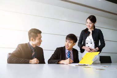 Tablo ve evrak ortağının imzalama ve karlı anlaşması yaptıktan sonra gülümseyerek oturan kendine güvenen iş adamı.