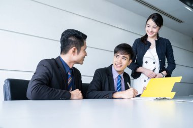 Tablo ve evrak ortağının imzalama ve karlı anlaşması yaptıktan sonra gülümseyerek oturan kendine güvenen iş adamı.