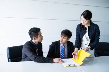 Tablo ve evrak ortağının imzalama ve karlı anlaşması yaptıktan sonra gülümseyerek oturan kendine güvenen iş adamı.