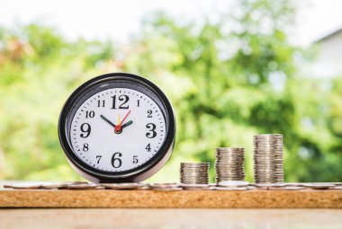 çalar saat ve adım para yığınları, Doğa arka plan, para, kaydetme ve siluet sesi flare yatırım veya aile planlaması kavramı, Güneş üzerinde.