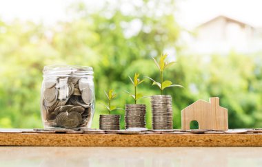 Ahşap ev modeli ve ağaç ve kavanoz, para, sikke Baca'ya adımında tasarruf ve yatırım veya aile planlaması kavramı.