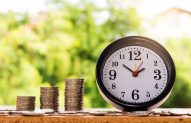 çalar saat ve adım para yığınları, Doğa arka plan, para, kaydetme ve siluet sesi flare yatırım veya aile planlaması kavramı, Güneş üzerinde.