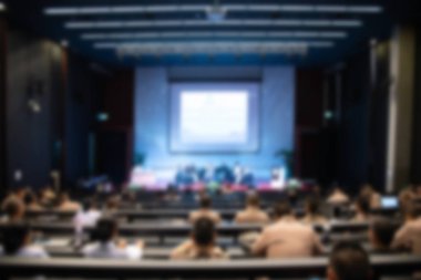 Konferans salonu veya seminer odasındaki iş adamlarının geçmişi bulanık.