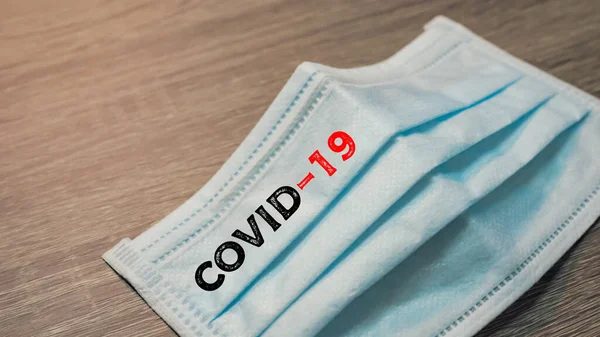 Inscription Covid-19 on Surgical mask with rubber ear straps. antivirus medical mask for protection covid-19. Protection corona virus concept.
