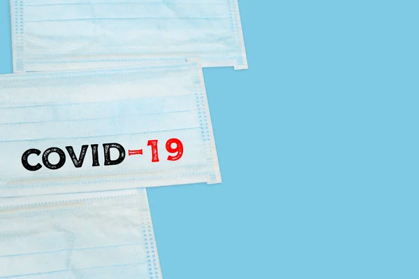 Inscription Covid-19 on Surgical mask with rubber ear straps. antivirus medical mask for protection covid-19. Protection corona virus concept.