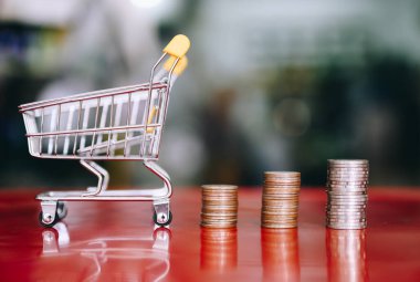 Bozuk para yığınları, para, alışveriş tasarrufu ve yatırım ya da aile planlaması içeren alışveriş arabası.