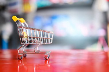 Süpermarket bulanık arkaplanı olan boş sarı alışveriş arabası.