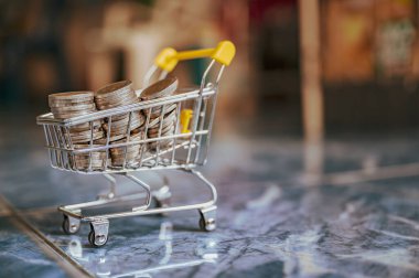 Sarı alışveriş arabasındaki para paraları soyut arkaplanı bulanıklaştırır.