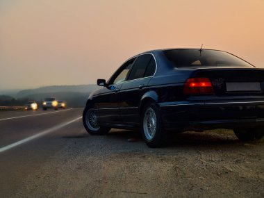 Gün batımında otoyolda bir araba.