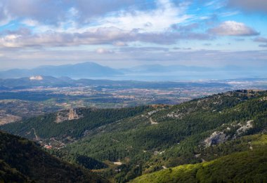 Yukarıdan panoramik ormanları ve EVIA Yunan Adası Deniz ile serpantin Köyü ve güneşli bir ufukta bulutlar