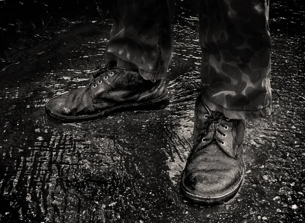 Old boots in a puddle in the rain on a black and white photo
