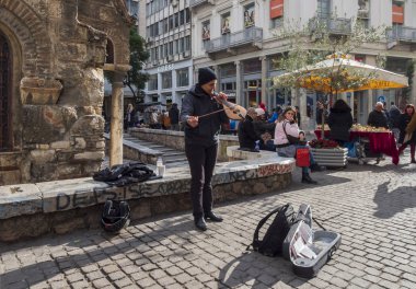 Atina, Yunanistan. 21 Aralık 2018: Ermou Caddesi - ana alışveriş caddesi güneşli kış günü Atina şehir, Sokak müzisyeni ile bir keman Kapnikarea Kilisesi, turistler ve alışveriş