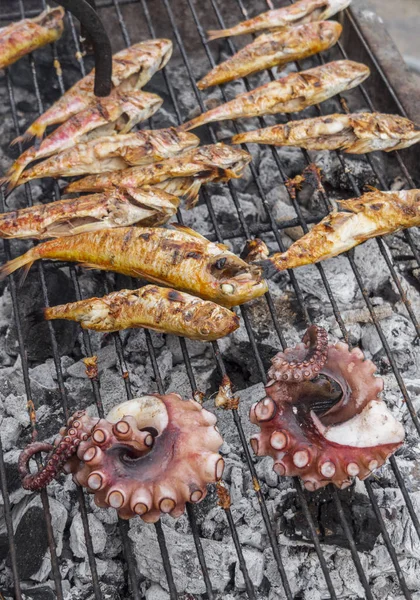 Octopus tentacles and fish with suction cups on grill closeup in Greek island