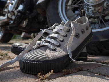 Kafatası ve gümüş bağcıklı gri spor ayakkabılar motosiklet helikopterinin direksiyonunda dikiliyordu.