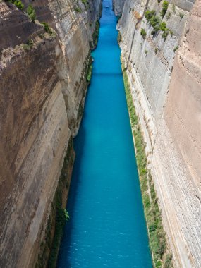 Yunanistan 'ın Mora kentindeki güneşli bir günde Corinth Kanalı' ndan geçen tekne ve yatların köprüden görünüşü