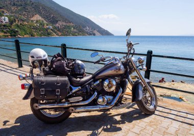 Loutra Edipsou, Evia Adası, Yunanistan. Eylül 2020: Bir motosiklet kruvazörü, bir Yunan adasındaki deniz ve dağların arka planına karşı bir Spa tatil beldesinin rıhtımında duruyor.