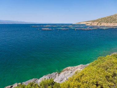 Ege Denizi 'nin kayalıklarından ve Yunanistan' ın Evia adasında güneşli bir günde bir balık çiftliği manzarası