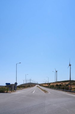 Yunanistan 'ın Evia adasında ufukta rüzgar türbinleri beliren asfalt otoyol