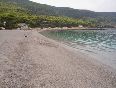 Porto Germeno, Yunanistan. Ekim 2020: Yunan köyü Porto Germeno ve güzel Agios Nikolaos plajının panoramik manzarası, Yunanistan 'da İyon Körfezi' nin Korint Körfezi 'nde bulutlu bir deniz üzerinde turistlerle 