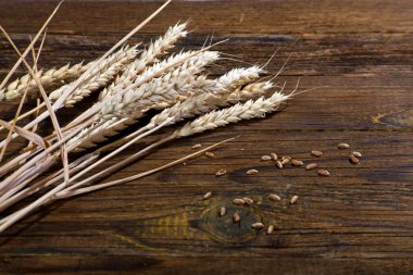 Eski bir ahşap masanın arka planında olgun buğday kulakları