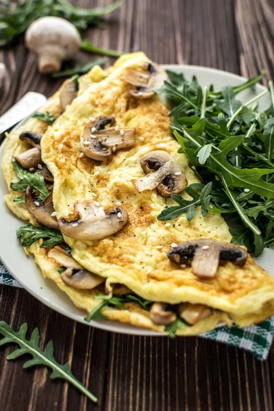 Mantar ve roka ahşap arka plan üzerinde ev yapımı omlet