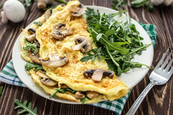 Mantar ve roka ahşap arka plan üzerinde ev yapımı omlet