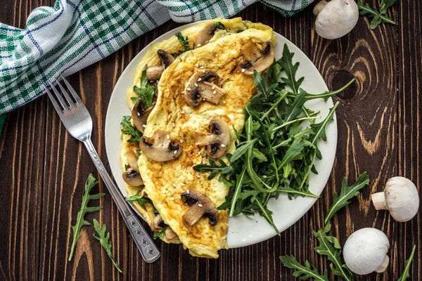 Mantar ve roka ahşap arka plan üzerinde ev yapımı omlet