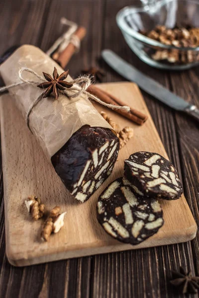 Chocolate sausage on a wooden background. Dessert made of biscuits, chocolate and nuts is sliced on a wooden board